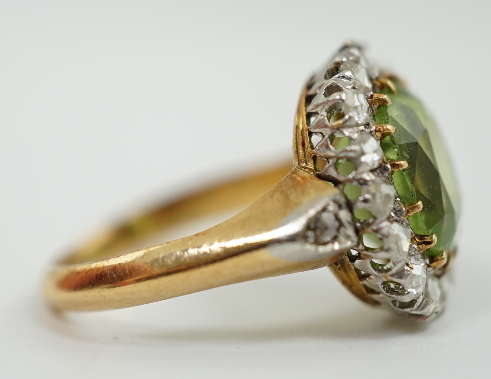 An early 20th century gold, peridot and diamond set oval cluster ring